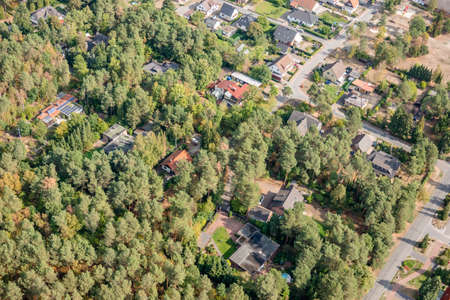 Aerial view of the edge of a village with small family houses, whose properties penetrate into the dense forestの写真素材