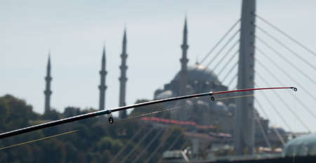 Fishing rod in front of the deliberately blurred backdrop of a mosque with dome and minarets