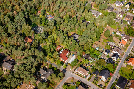 Aerial view of the edge of a village with small family houses, whose properties penetrate into the dense forestの写真素材