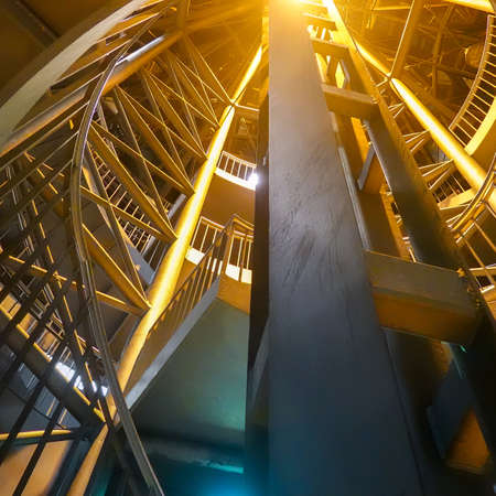 Night-time recording of the illuminated spiral staircase leading from the platform of an underground to the outside of the building.の写真素材
