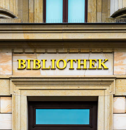 Entrance of a library in an ancient building labeled with golden lettersの写真素材