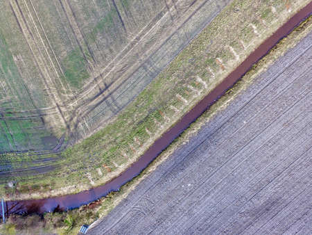 Graphic and abstract aerial view of an artificially straightened stream, which lies between...