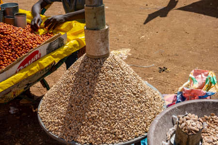 Sales pyramid of artfully stacked sunflower seeds with tin cans on top at a market in Africa.