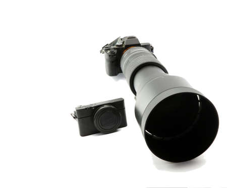 Mirrorless blac system camera with ultratele telezoom 150mm to 600mm and tiny compact camera in comparisonの写真素材
