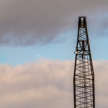 Upper part of a crane in the harbor in front of a cloudy sky, abstractの写真素材