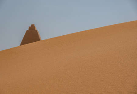 Tip of a pyramid behind a dune in Sudan