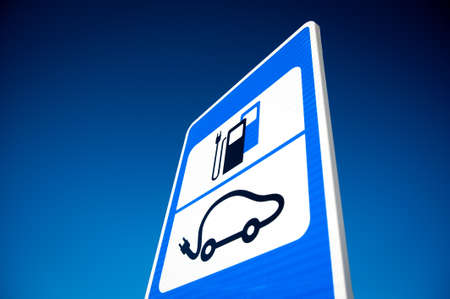 Road sign of electric car battery recharge station over deep blue sky background