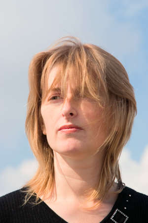 Young blonde woman against cloudy sky