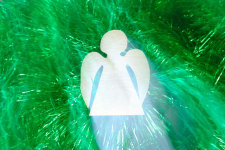 Flying paper angel against green tinsel, Christmas concept, lighting effectsの写真素材