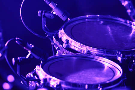 Rock concert series: drum set with microphones, lit by purple and blueの写真素材