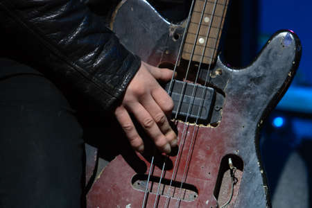 Rock concert: hand of musician, playing old bass guitarの写真素材