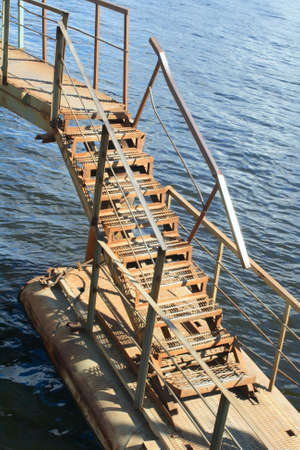 Rusty metal ladder of pontoon bridge over waterの写真素材