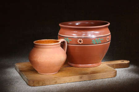 Ceramic pots on wooden cutting board, on sackcloth