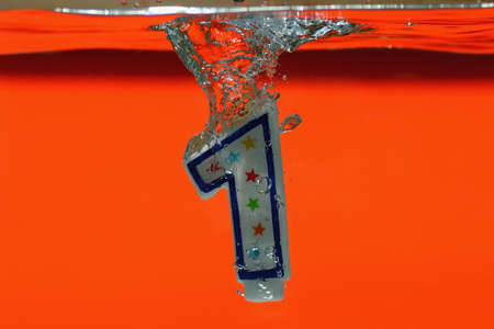 High-speed photo of candle frozen in time as it is splashing into crystal clear water.  Narrow DOF.