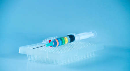 Disposable syringe with multicolored liquid on blue backgroundの写真素材