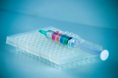 Medical syringe with colored liquid close-up on a blue background