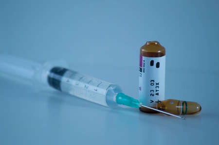 A syringe with a vaccine and an ampoule on a blue backgroundの写真素材