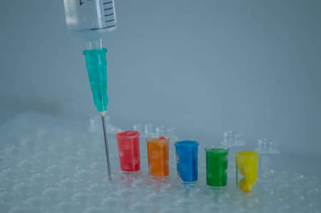 Close-up of plastic syringe with multicolored liquid in it.