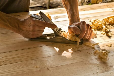 Joinery. Planing a natural wood furniture panel with a manual planer. Hands with a planer.