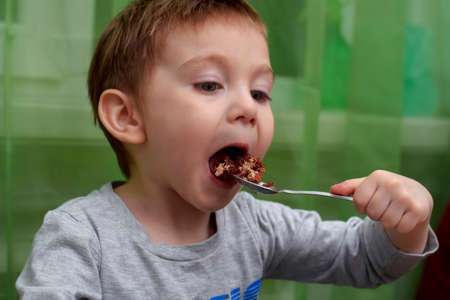 Close up of lovely two year old baby eating with a spoon