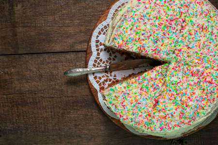 Cake with colored sprinkles, a blue plate with a piece of cake, a mug with tea, cutlery and a napkin...