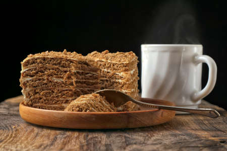 Honey cake and a cup of coffee on a wooden table. On a black background.の写真素材