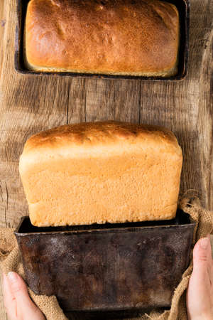 Hands shaking out white bread from a baking dish still lifeの写真素材