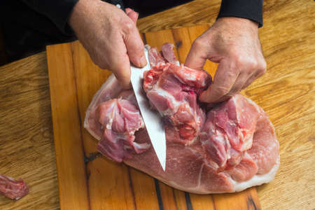 The cook cuts a large knife pork ham on a cutting board.