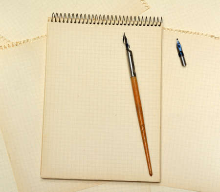 Old ink pen and notebook on background with sheets of paperの写真素材