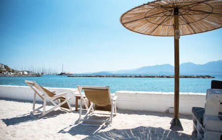 Two Deckchairs Under Parasol In Tropical Beach at quiet seaの写真素材