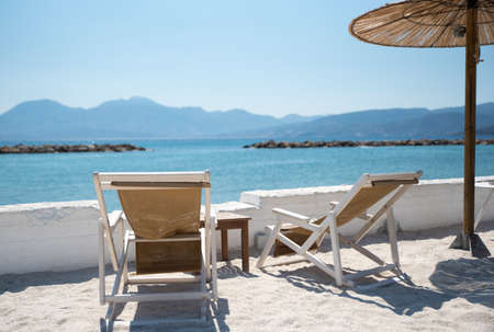 Two Deckchairs Under Parasol In Tropical Beach at quiet seaの写真素材