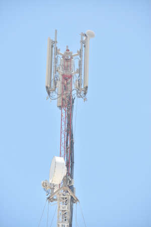 Close up of Cell tower and radio antenna in trees against a blue sky.Abu dhabi,UAE.16.06.2020.の写真素材