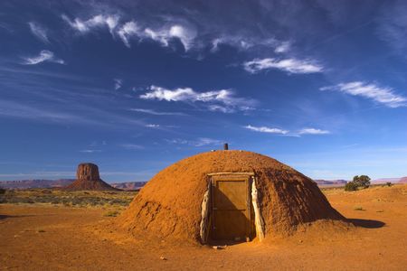 Hogan, the traditional Navajo red clay earth house, with backdrop of famous table mountains of the Navajo National monument on the backgroundの写真素材