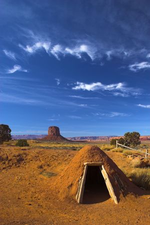 Hogan, the traditional Navajo red clay earth house, with backdrop of famous table mountains of the Navajo National monument on the backgroundの写真素材