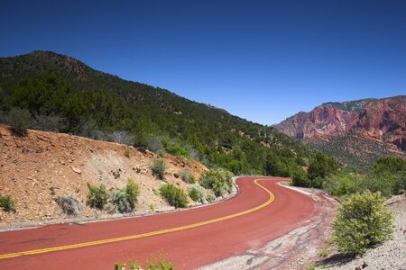 Red road to the mountains of the Zion National parkの写真素材