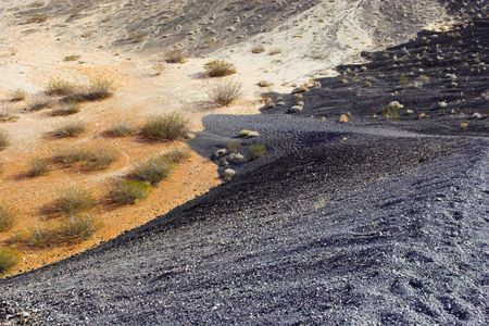 Fragment of black lava and ornage clay and salt mineral deposits in geological formations in Ubehebe Volcano, Death Valley National Parkの写真素材