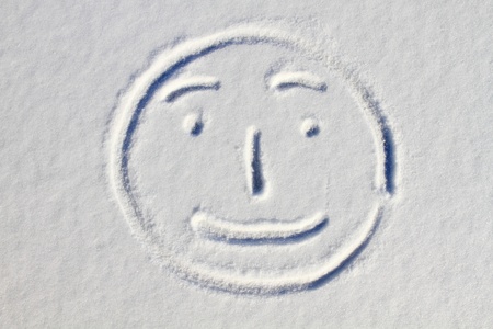 Smiley face drawn on snow backgroundの写真素材