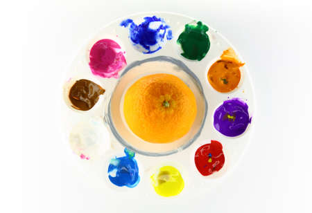Round artist palette with orange fruit  in the middle on white backgroundの写真素材