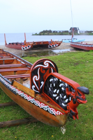 Traditional Maori wood carved canoes on the shore in New Zealand in rainy weatherのeditorial素材