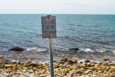 The phrase Live for Today is printed on the inspirational signpost on the shore with ocean backgroundの写真素材