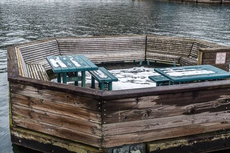 A view of a picnic area on the water with benches and tables. Shot taken at Coulon Park in Renton,...