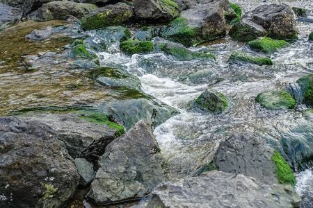 A macro shot of a stream flowing over boulders.の写真素材