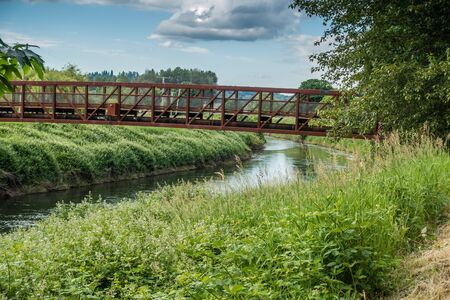 A rusted metal bridge spans the Green River in Kent, Washington.の写真素材