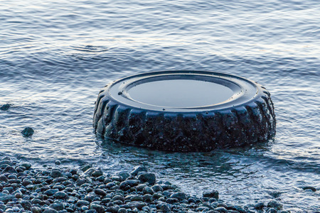 A large tire sits in the water near shore in West Seattle, Washington.の写真素材