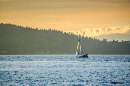 A sailboat moves across the Puget Sound with hills in the distance.の写真素材