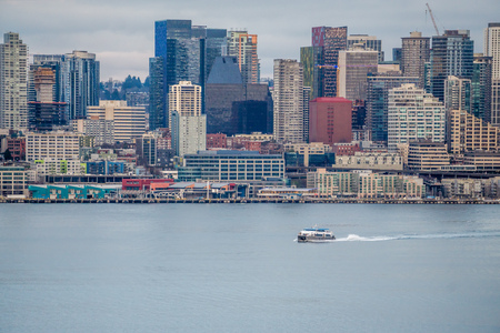 A boat cruises across Elliott Bay in front of the Seattle skyline.の写真素材