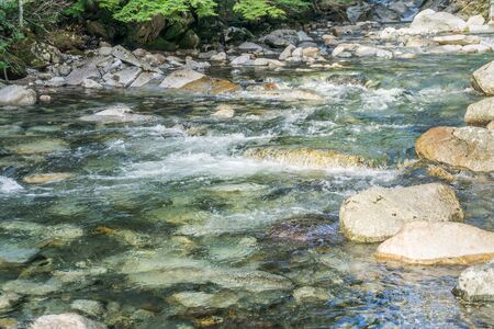 Clear water flows past and over rocks in Denny Creek in Washington State.の写真素材