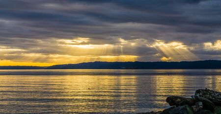 Rays of sunligh break through dark clouds over the Puget Sound in Washington State.
