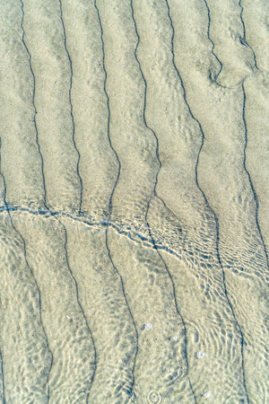 Ocean water forms patterns over sand as it reaches shore in Moclips, Washington.の写真素材