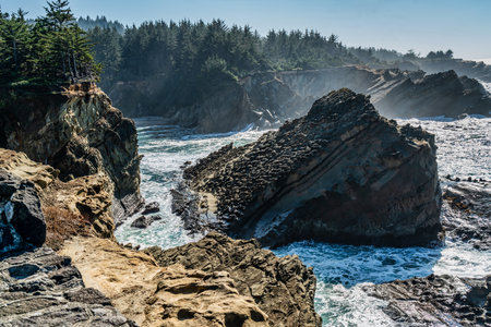 A view of the shoreline with rock formations and crashing waves at Shore Acres State Park in Oregon...